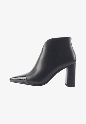 Juodi odiniai aulinukai iki kulkšnies su smailiu nosiu, blizgiu patentu akcentu ir vidutinio aukščio kvadratiniu kulnu. Lygi tekstūra ir elegantiškas dizainas.