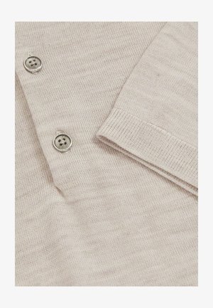 Ljusbeige cardigan med en finstickad textur. Har tre metallknappar och ribbade ärmslut för en strukturerad finish.