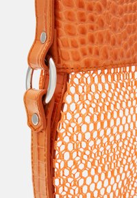 Sac à main orange avec un dessus en cuir à motif crocodile texturé, quincaillerie en métal et une section inférieure en maille en forme de nid d'abeille.