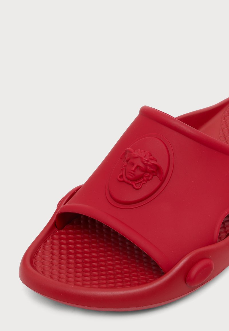 Sandalo slide rosso con soletta testurizzata e emblema in rilievo con testa di Medusa sulla fascia, realizzato in materiale gommoso liscio.