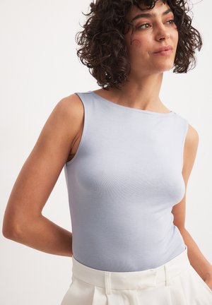 Light blue sleeveless top made of smooth fabric, featuring a round neckline and a fitted silhouette, paired with high-waisted white trousers.
