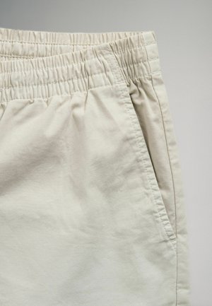 Lyse beige shorts med elastisk taljebånd, sidelomme og et glat, let tekstureret stof. Skræddersyet design med en afslappet pasform.