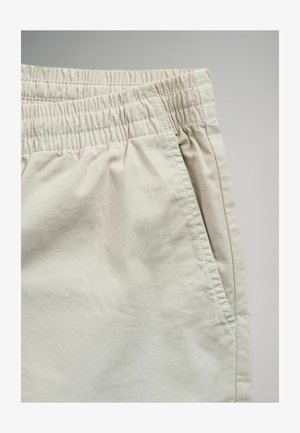 Hellbeige Shorts mit elastischem Bund, Seitentasche und einem glatten, leicht strukturierten Stoff. Maßgeschneidertes Design mit lässiger Passform.