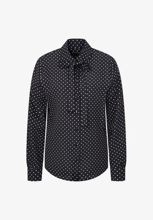 Czarna bluzka z długim rękawem w białe kropki, z zapięciem na guziki z przodu i wiązaną kokardą przy kołnierzyku.