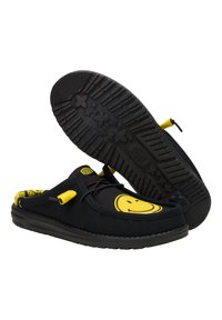 Scarpe nere slip-on con accenti gialli, con un design di faccina sorridente sulla parte anteriore e una suola in gomma testurizzata con modelli antiscivolo.