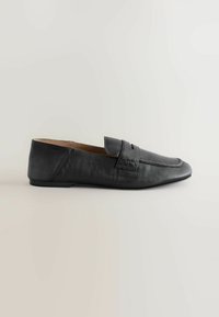 Black leather loafer with a low heel, rounded square toe, and a stitched strap across the vamp, displayed on a plain light background.