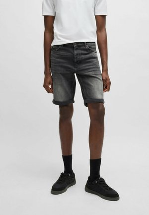 Black denim shorts with rolled hems, featuring a classic five-pocket design and slight fading, paired with a white t-shirt and black sneakers.