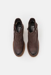 Botas de tobillo de cuero marrón con superficie texturizada, punta redondeada, cremallera lateral y acento de hebilla de metal. Presenta una suela contrastante.
