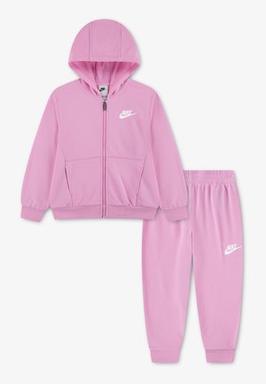 Pink Nike børne træningsdragt med lynlåshætte og joggers med elastisk talje, med hvide Nike-logoer på bryst og venstre ben.