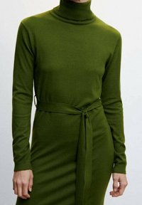 Robe à manches longues vert olive avec un col montant et une ceinture nouée à la taille, en matériau lisse et doux, présentant une silhouette ajustée.