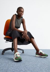 Sportovní tenisky s zeleno-bordó barevným schématem a bílými detaily, vyrobené z měkké semišové látky a s texturovanou gumovou podrážkou.