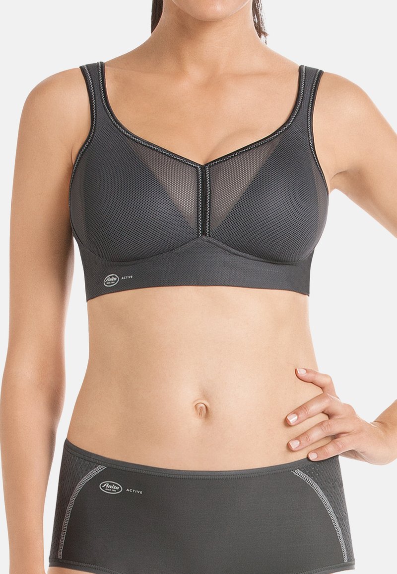 Schwarzer Sport-BH mit einem Netzdesign, verstellbaren Trägern, V-förmigem Ausschnitt und kontrastierenden Nähten. Kombiniert mit passenden tief sitzenden Slips.