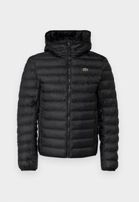 Černá prošívaná bunda s překrytým zipem a kapucí. Má horizontální prošívaný vzor, elastické manžety a malý zelený znak na hrudi.