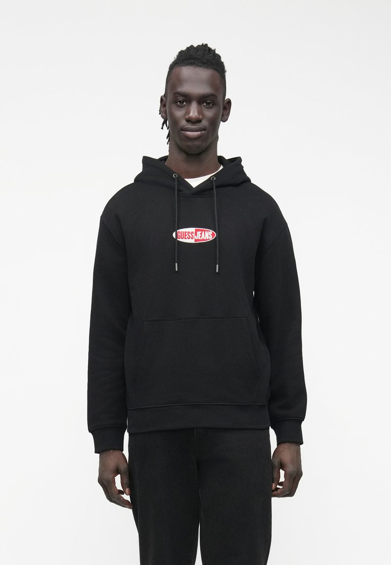 Μαύρο φούτερ με κουκούλα από βαμβακερό μείγμα, με μπροστινή τσέπη τύπου καγκουρό και κόκκινο λογότυπο "GUESS JEANS" στο στήθος.