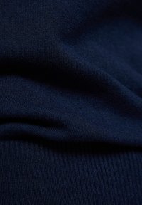 Marineblaue Strickware mit glatter Textur und gerippten Details. Zeigt subtile Variationen in der Webart, die eine Farbentiefe erzeugen.