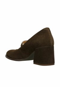 Hnědá semišová dámská obuv na podpatku s kulatou špičkou a širokým blokovým podpatkem. Na boku má výřezový motiv pro doplnění detailu. Hladká textura.