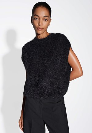 Top nero senza maniche in maglia con una texture soffice e scollo arrotondato, abbinato a pantaloni neri. Design minimalista con una leggera lucentezza.