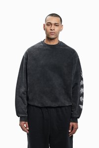 Black sweatshirt with a relaxed fit, featuring a textured fabric and white graphic design on the left sleeve. Ribbed collar and cuffs.