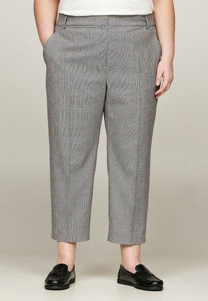Grau karierte Hose mit einer verkürzten Passform, subtiler Struktur, seitlichen Taschen und kombiniert mit schwarzen Mokassins.