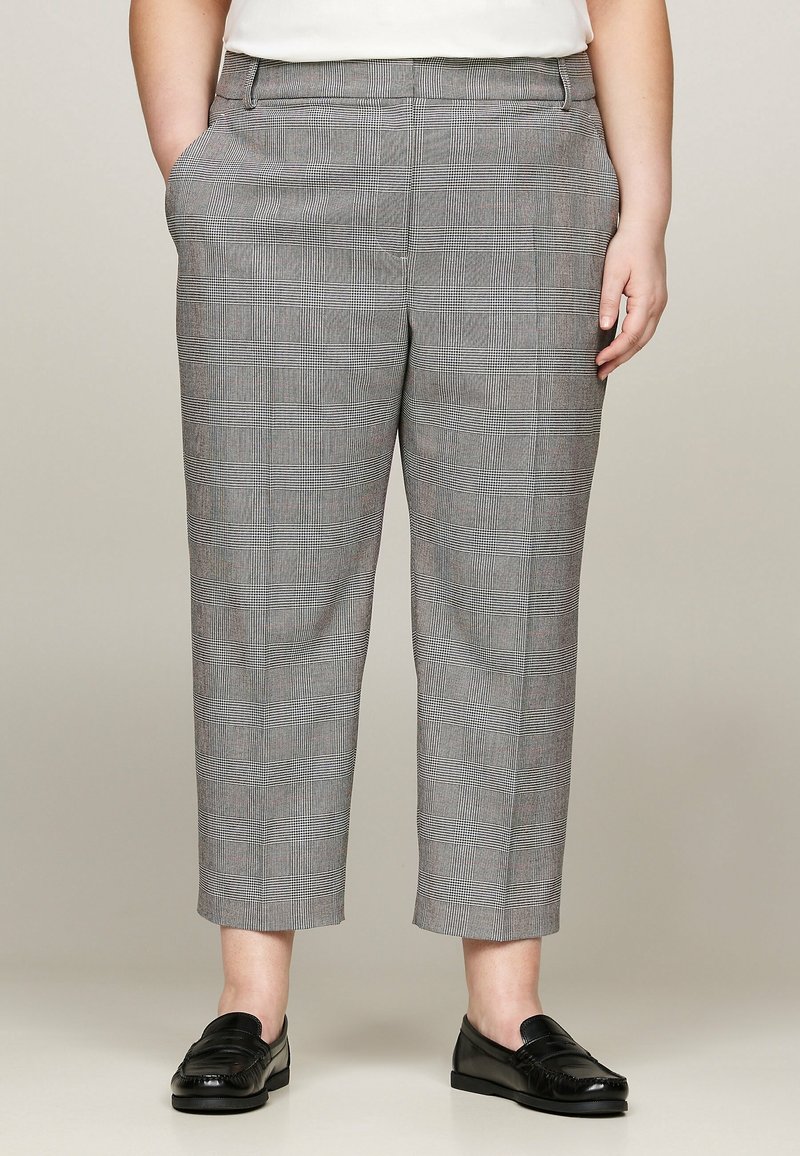 Šedé kostkované kalhoty s zkráceným střihem, jemnou texturou látky, postranními kapsami a v kombinaci s černými mokasíny.