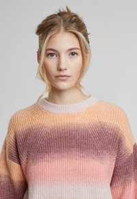 Gebreide trui met een gradientpatroon in perzik, roze en mauve. Geribbelde textuur met een ronde halslijn en een comfortabele pasvorm.
