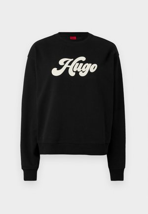 Svart sweatshirt i mjukt tyg, med en stor vit "Hugo"-logotyp i en böjd font. Ribbad halsringning, ärmslut och nederkant. Klassisk passform.