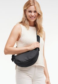 Borsa a tracolla in tessuto nero, design curvo con texture liscia, caratterizzata da un dettaglio con logo. Cinghia regolabile da indossare sulla spalla.