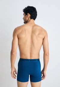 Boxer da uomo blu di Björn Borg, con elastico nero con logo. Tessuto liscio, design aderente e taglio di lunghezza media con cuciture minime.