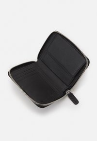 Portefeuille en cuir noir avec fermeture éclair, doté de fentes pour cartes et d'une texture lisse, présenté avec un intérieur ouvert. Design globalement minimaliste.