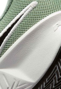 Κοντινή λήψη ανοιχτοπράσινου υφάσματος δίχτυ με λευκές και μαύρες κεντητές λεπτομέρειες σε υφασμένη λευκή λαστιχένια σόλα.