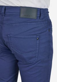 Slank-fit navyblauwe broek van lichtgewicht stof, met een leren label op de tailleband en achterzakken met zichtbare stikseldetails.