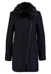 Mörk marinblå kappa med sned framdragkedja och stor svart fuskpälskrage, långa ärmar och sidofickor.