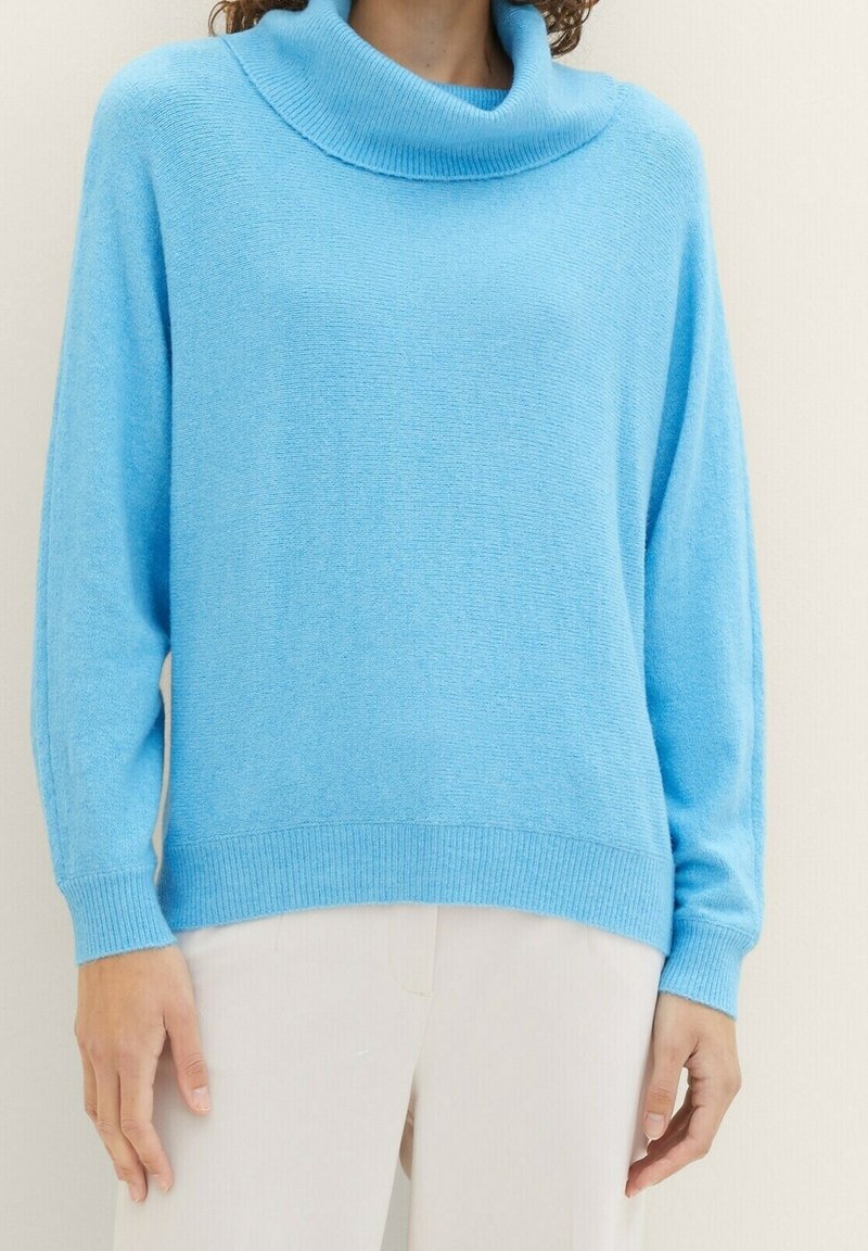 Ljust blå cowl-neck tröja gjord av mjukt, strukturerat tyg. Har långa ärmar och ribbade muddar och fåll för en bekväm passform.