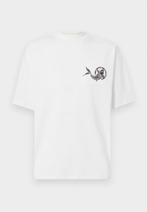 T-shirt bianco in cotone con scollatura rotonda, caratterizzato da una grafica colorata di un drago stampata nell'area sinistra del petto. Maniche corte.