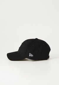 Black corduroy cap with a curved brim, featuring an embroidered logo on the front and a small logo tag on the side.