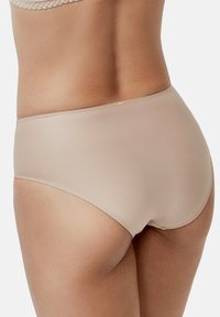 Beige high-waisted slipjes van soepel elastisch materiaal, met een zachte textuur en minimale stiksels, en een subtiele gouden accenten bij de tailleband.