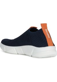 Zapatilla azul marino con un parte superior de punto texturizado, suela de goma blanca y una lengüeta naranja en el talón con la marca 'GEOX'.