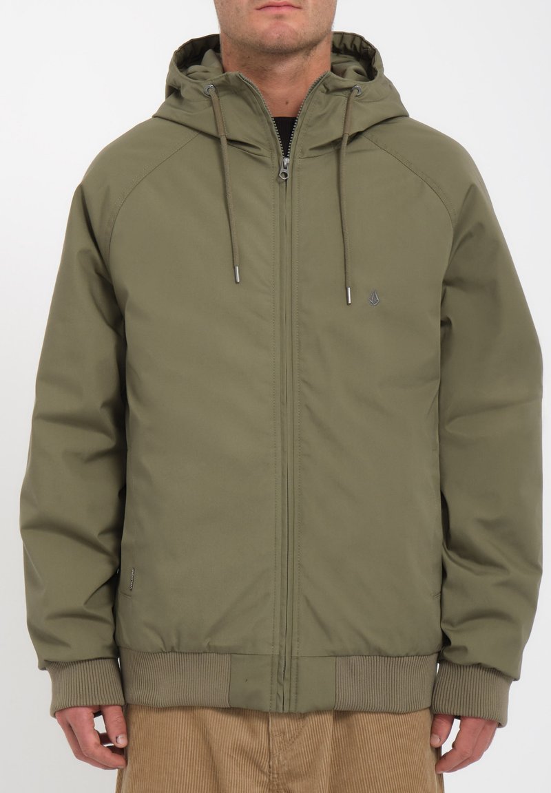 Olijfgroene hoodie met een voorzijde rits, ribbelmanchetten en -tailleband. Heeft een subtiel logo en een gladde textuur.