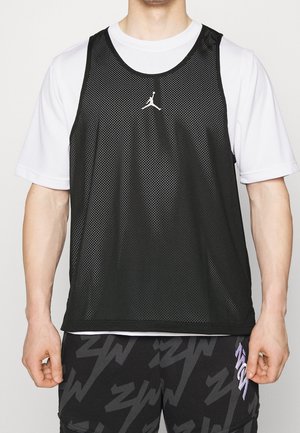 Débardeur de sport en maille noire avec un logo Jumpman blanc, superposé à une chemise à manches courtes blanche. Il présente un col arrondi et des emmanchures larges.