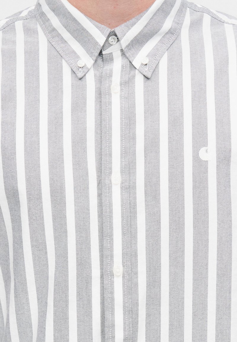 Camicia a righe grigie e bianche con bottoni e colletto classico, caratterizzata da un piccolo logo sul petto e tessuto testurizzato.