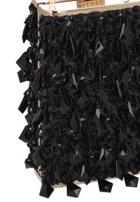Pochette noire perlée avec une surface texturée, ornée de perles géométriques noires brillantes et d'un fermoir doré en haut.