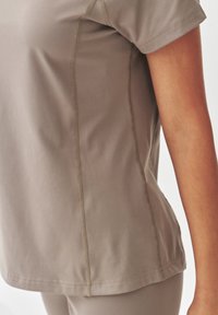 Lichtbruine sportshirt met korte mouwen, voorzien van contrasterende naden en een gladde, rekbare stof.