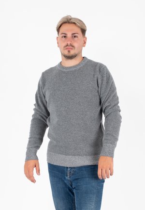 Maglione grigio lavorato a maglia con collo rotondo, maniche lunghe e bordi a coste; indossato con jeans blu su uno sfondo bianco uniforme.