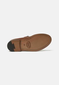 Sole di scarpa in pelle marrone con bordi cuciti, tacco in gomma nera e dettagli del marchio e della taglia impressi su uno sfondo bianco.