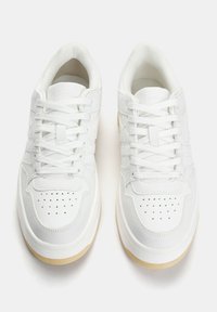 Sneaker bianche con tomaia in pelle testa di moro, punta forata, lacci piatti e suola in gomma beige chiaro. Design semplice con dettagli discreti.