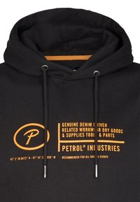Čierna mikina s kapucňou s oranžovým textom "Petrol Industries" a detailmi o džínsovej móde, pracovnom oblečení, náradí a pretekárskych podujatiach, s šnúrkami a kovovými špičkami.
