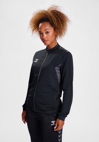 Schwarze Sportjacke mit Reißverschluss, langen Ärmeln und Kontrastpaneelen. Verfügt über ein Logo auf der Brust und an der Seite, kombiniert mit passenden Hosen.