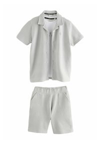 Lys grå to-dels outfit bestående af en kortærmet skjorte med knapper og matchende shorts, begge med et struktureret mønster og sidelommer.