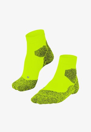 Helle, gelbe Knöchelsocken mit schwarz gesprenkelten Mustern an Zehen, Fersen und Seiten, mit einem gerippten Bündchen und dezenten grauen Nähdetails.