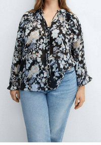 Black floral blouse with blue and beige flowers, featuring a button-down front, ruffled neckline, and long sleeves. Paired with light blue jeans.